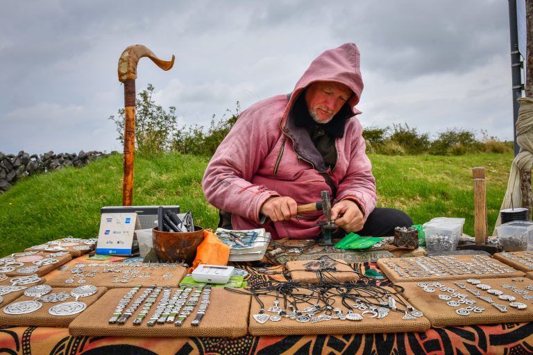 Irish master craftsman Tomas O'Cadhain hammers silver jewelry at the entrance to a 5,000 year old mini Stonehenge